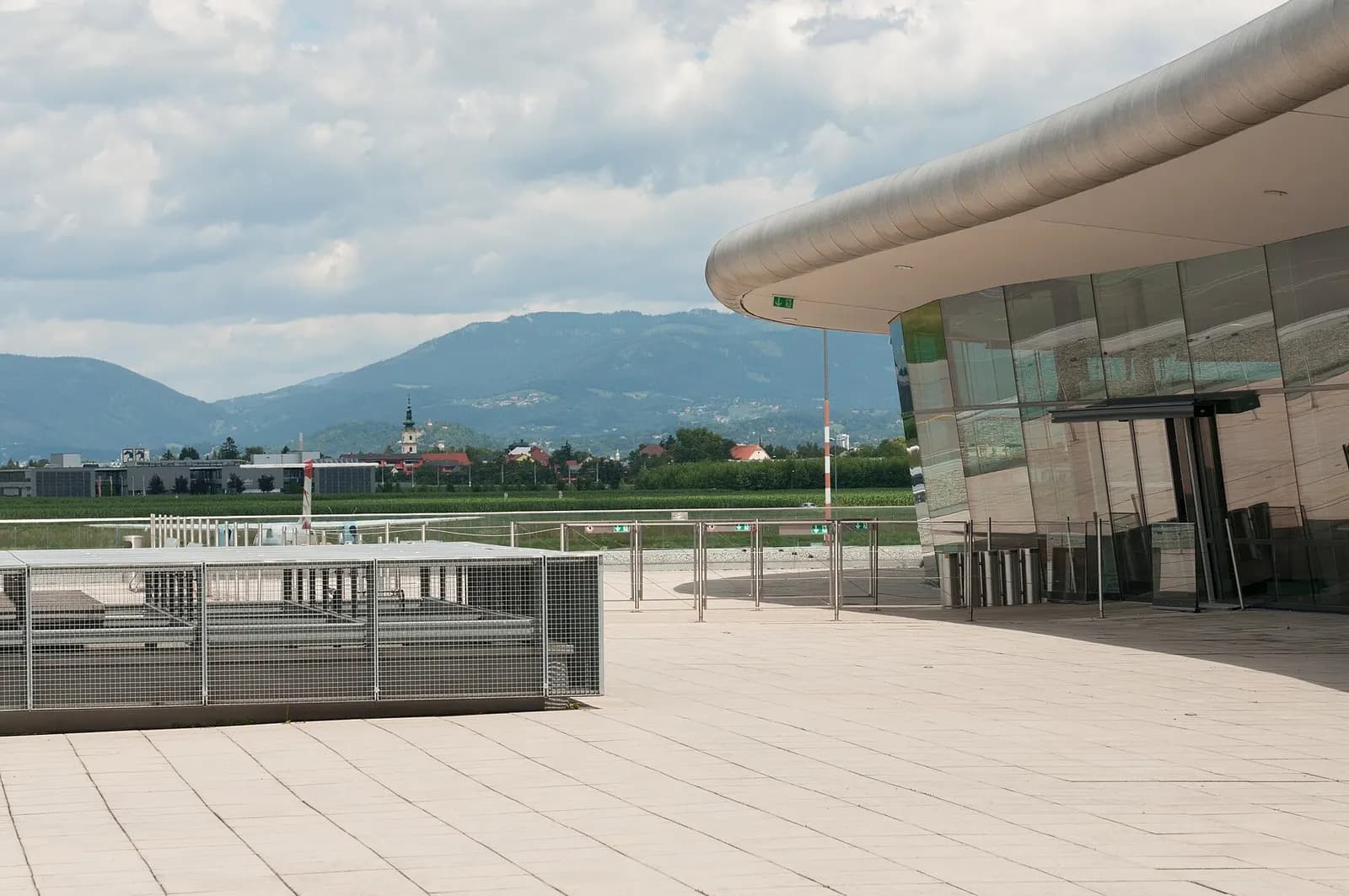 Public terrace outside the glass terminal facade overlooking Styrian hills