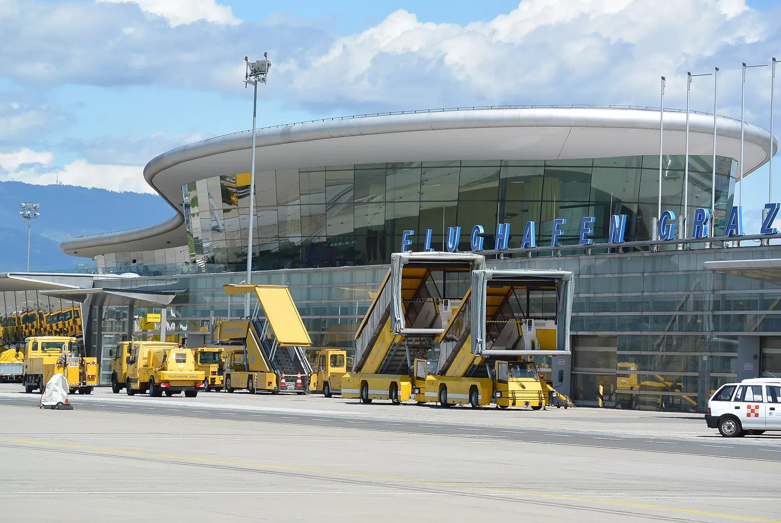 Airside face of the Graz terminal with FLUGHAFEN GRAZ lettering and yellow stairs
