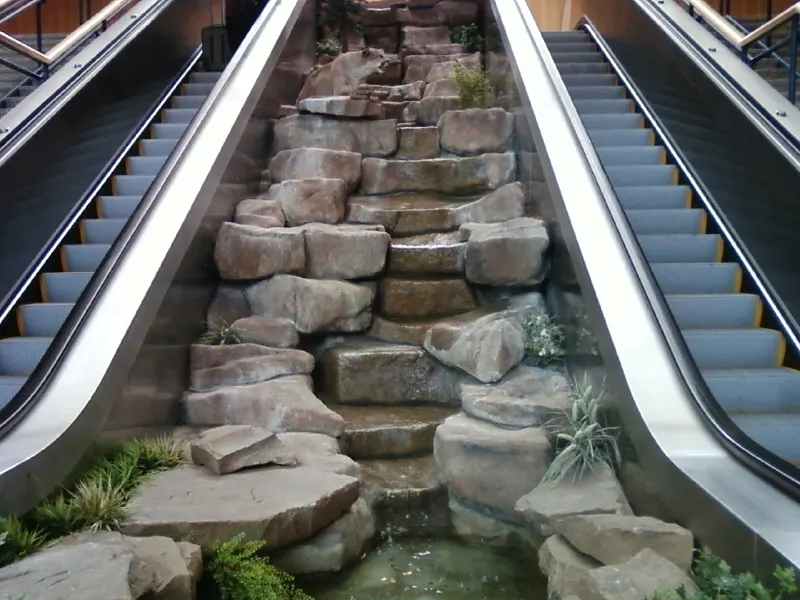 Fountain and paired escalators inside the Great Falls International Airport terminal hall.