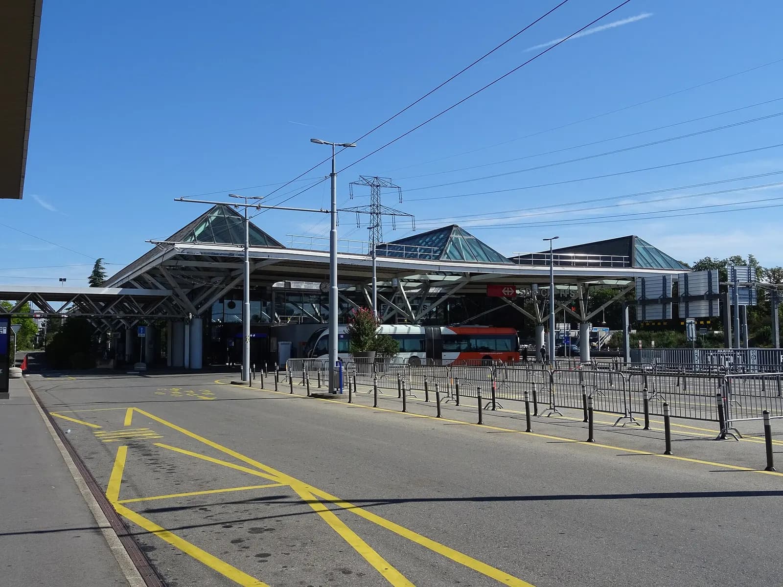 The Genève-Aéroport railway station passenger building and forecourt with signage pointing toward Terminal 1.