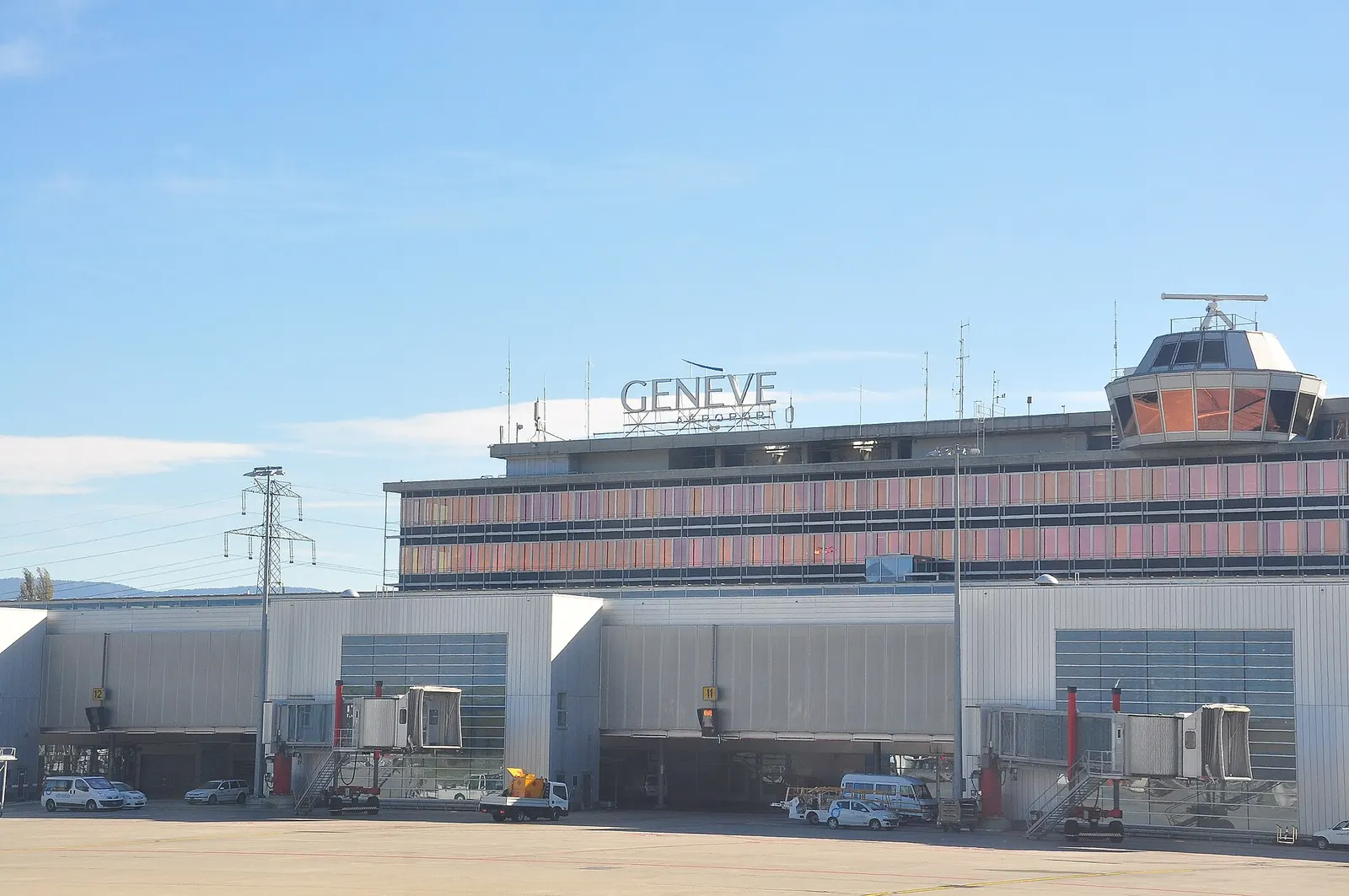 The main terminal buildings and control tower of Geneva International Airport seen from the landside approach.