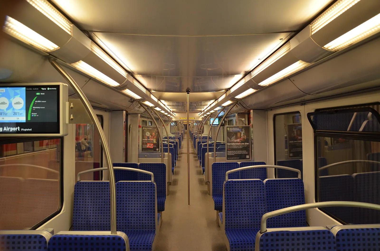 The bright, modern interior of a refurbished DB Class 474 S-Bahn carriage with seating and handrails.