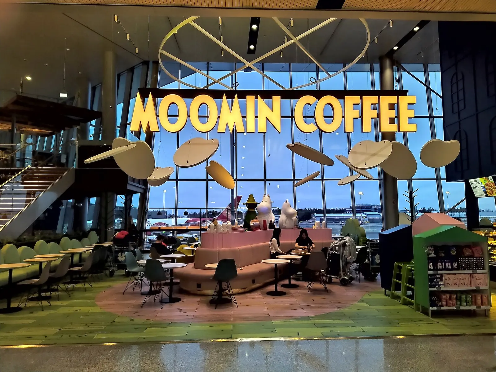 A Moomin-themed coffee shop inside the terminal decorated with large Moomin character figures and Finnish design.