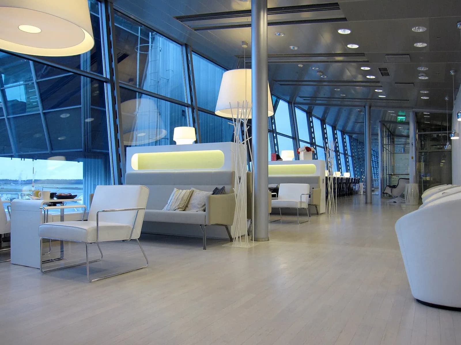 The Finnair lounge interior with seating clusters, tables, and large windows overlooking the airfield.