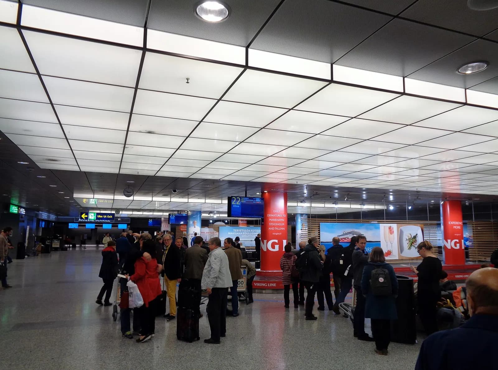 Baggage reclaim hall 2A with multiple carousels, overhead signs, and arriving passengers waiting for luggage.