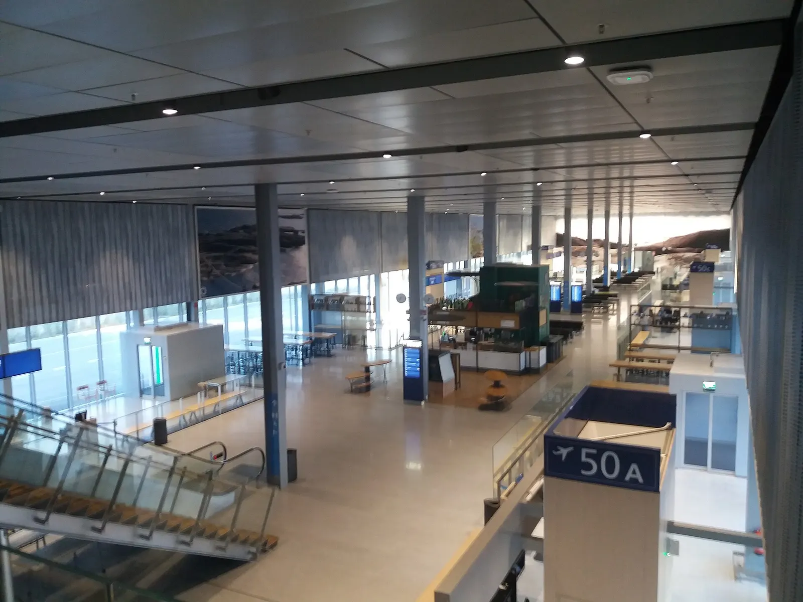 Indoor waiting area at the non-Schengen bus-gate terminal with seating and signage for remote stand departures.