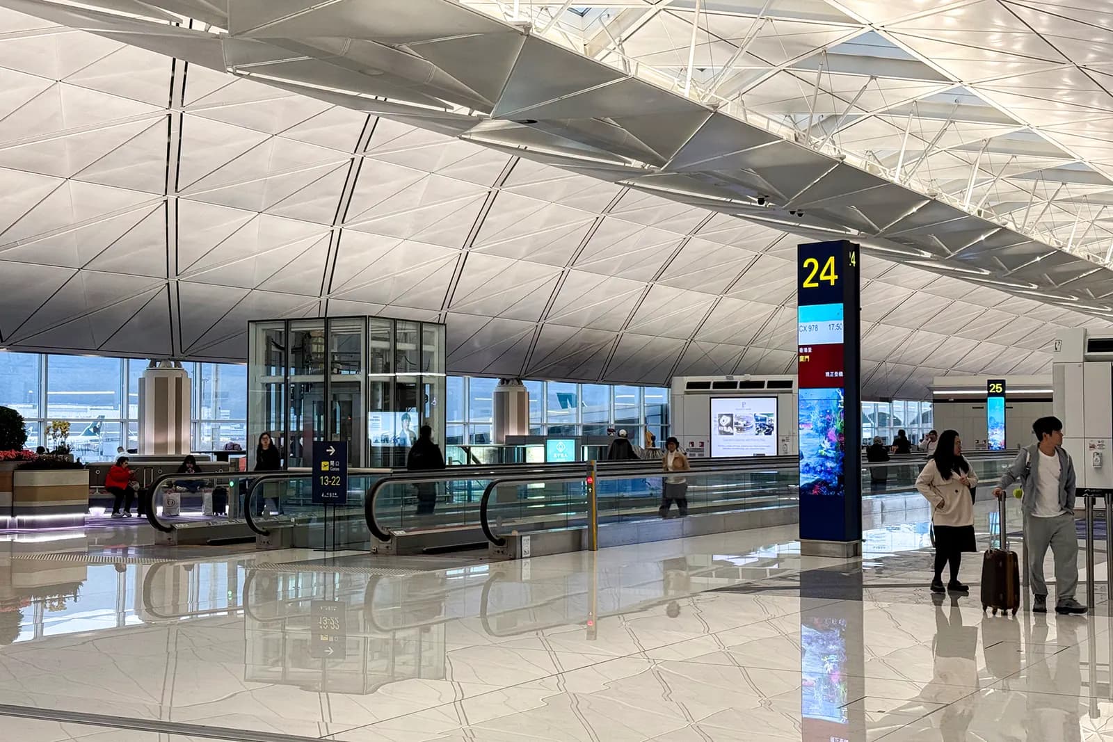 Bright, spacious interior of Terminal 1 with high ceilings, departure signage, and travelers moving through the main concourse.