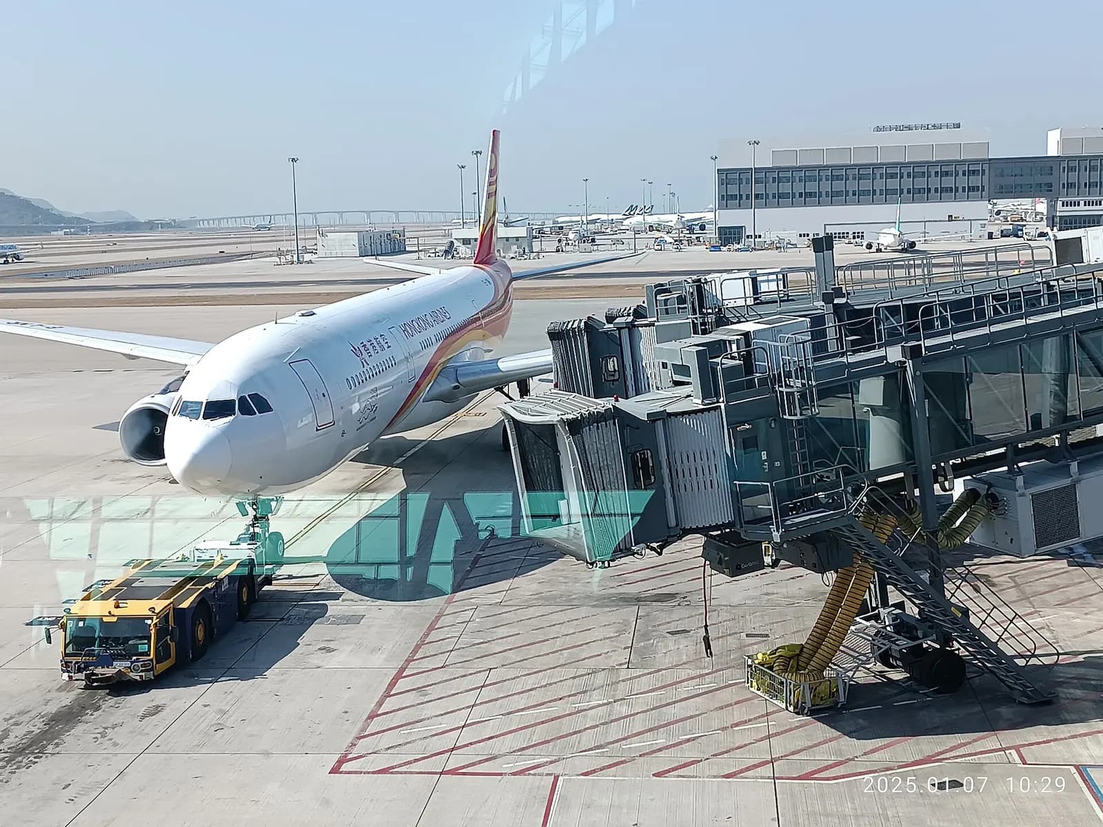 View through floor-to-ceiling windows in the departure lounge toward aircraft parked on the apron.