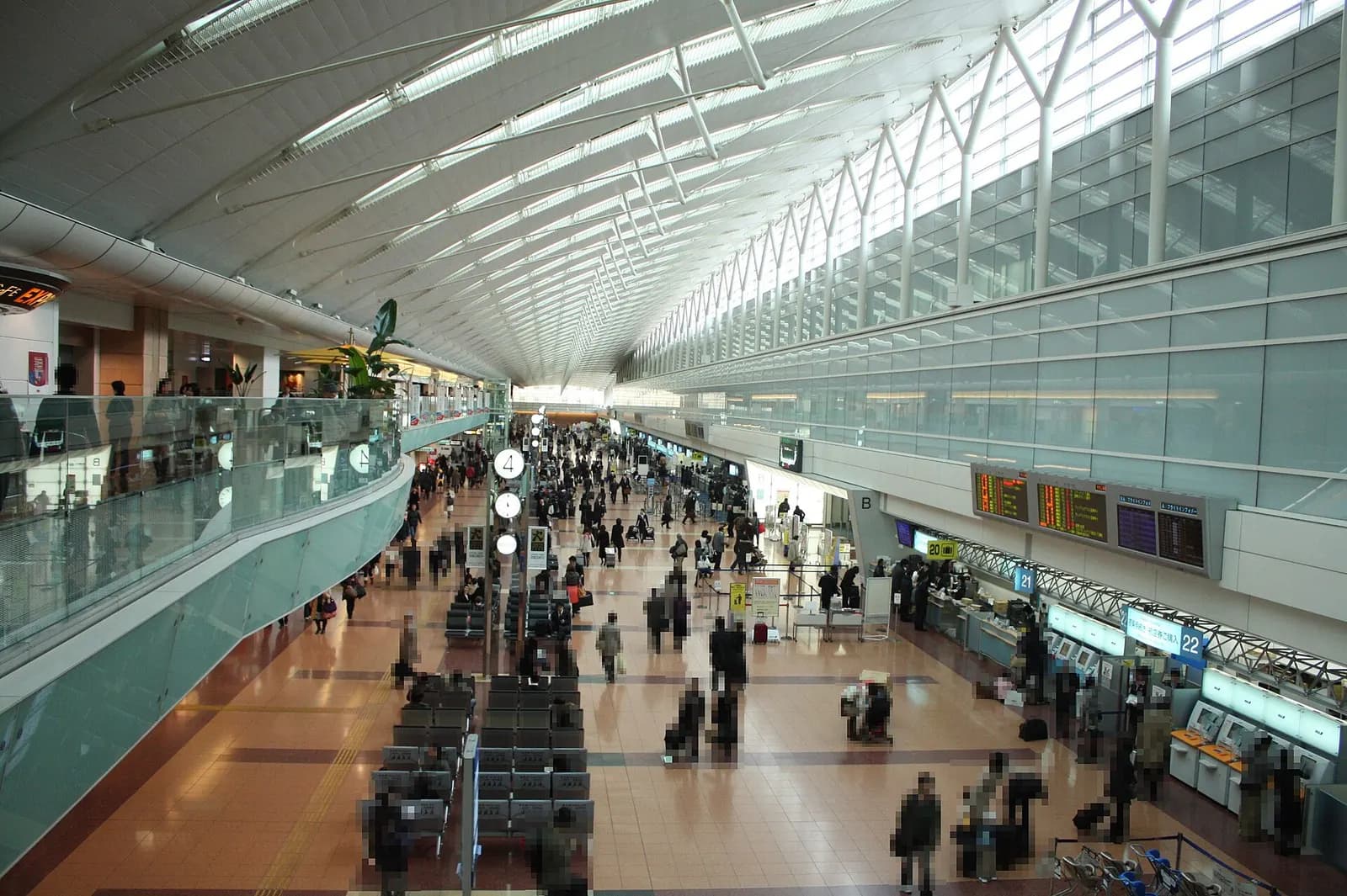 Row of airline check-in counters in Haneda Terminal 2 departure hall with signage, queue lanes, and passengers at desks.