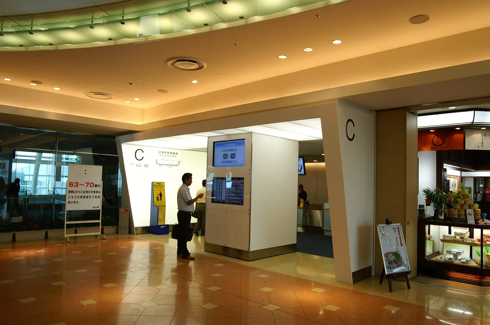 Security screening checkpoint in Terminal 2 with X-ray belts, metal detectors, and passengers waiting in organized lanes.