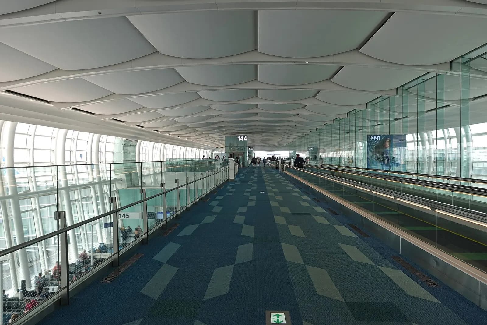 Bright, modern interior of Haneda Airport Terminal 3 with open concourses, signage, and travelers moving through the international terminal.