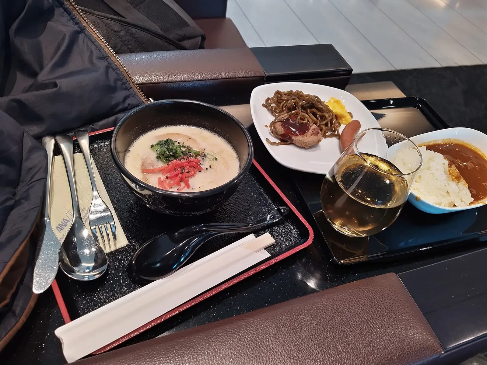 Buffet spread of hot meals, rice dishes, and side plates inside the ANA international departure lounge at Haneda.