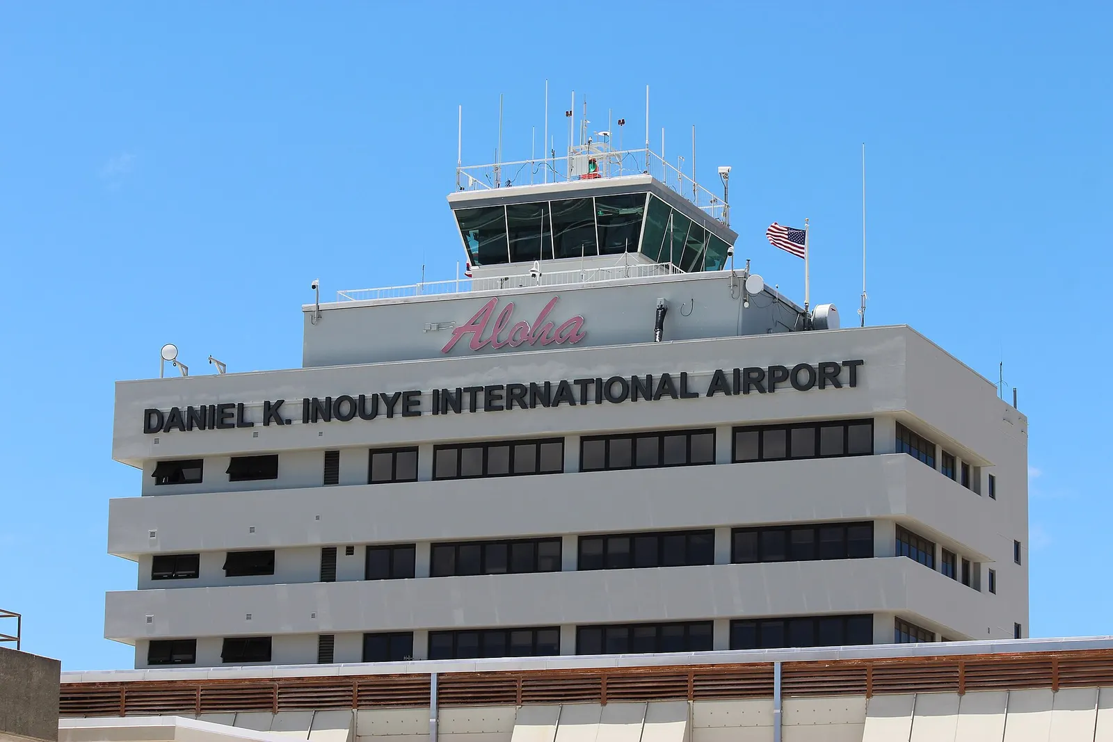 The main air traffic control tower of the Daniel K. Inouye International Airport (HNL) in 2025. Photo taken from the eastern concourse leading to the E gates. The other side of the tower also bears the name of the airport, but without the "Aloha" sign (there was formerly a digital clock where the "A
