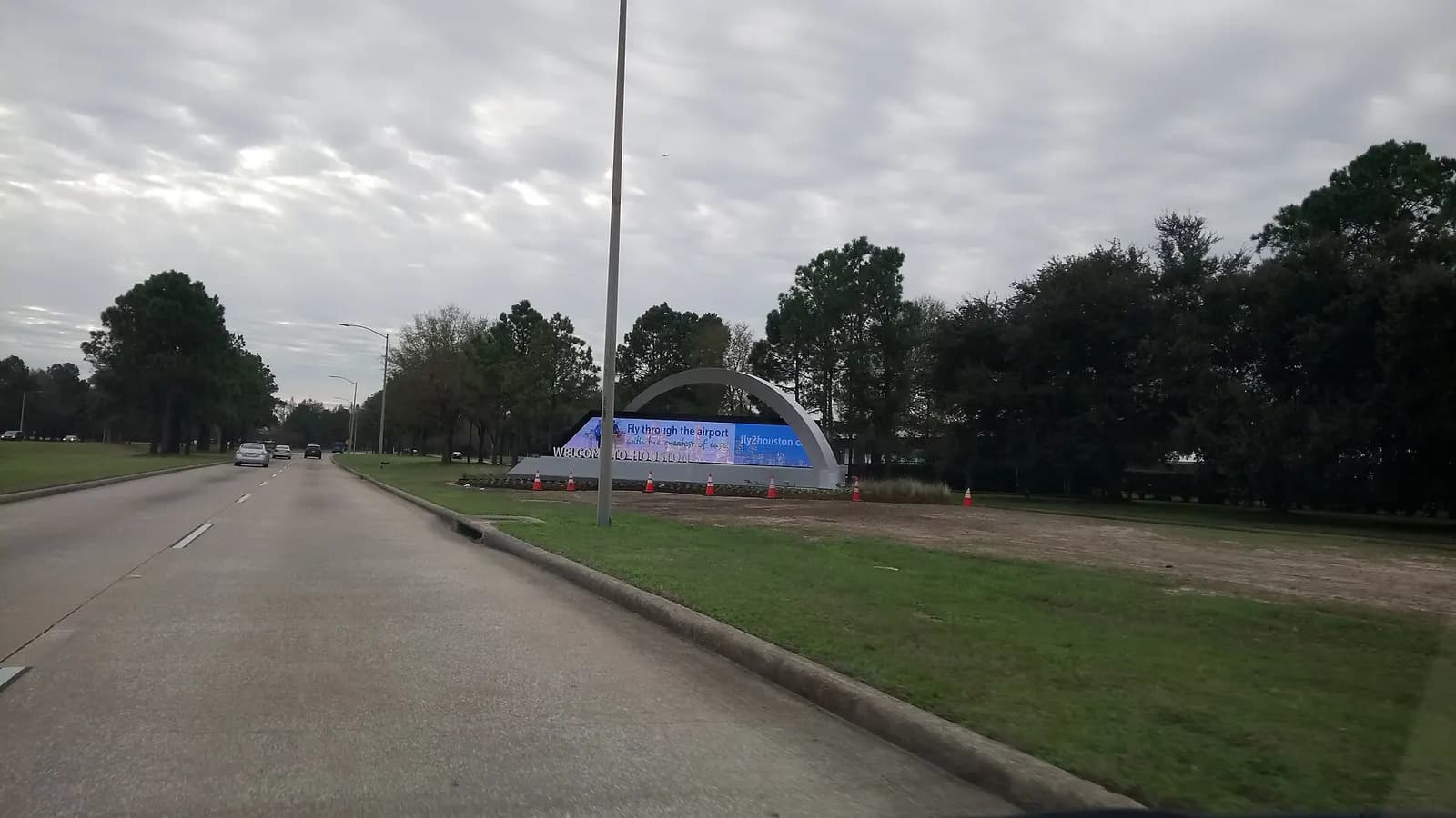 A large illuminated Welcome to Houston sign inside the airport terminal with travelers passing nearby.