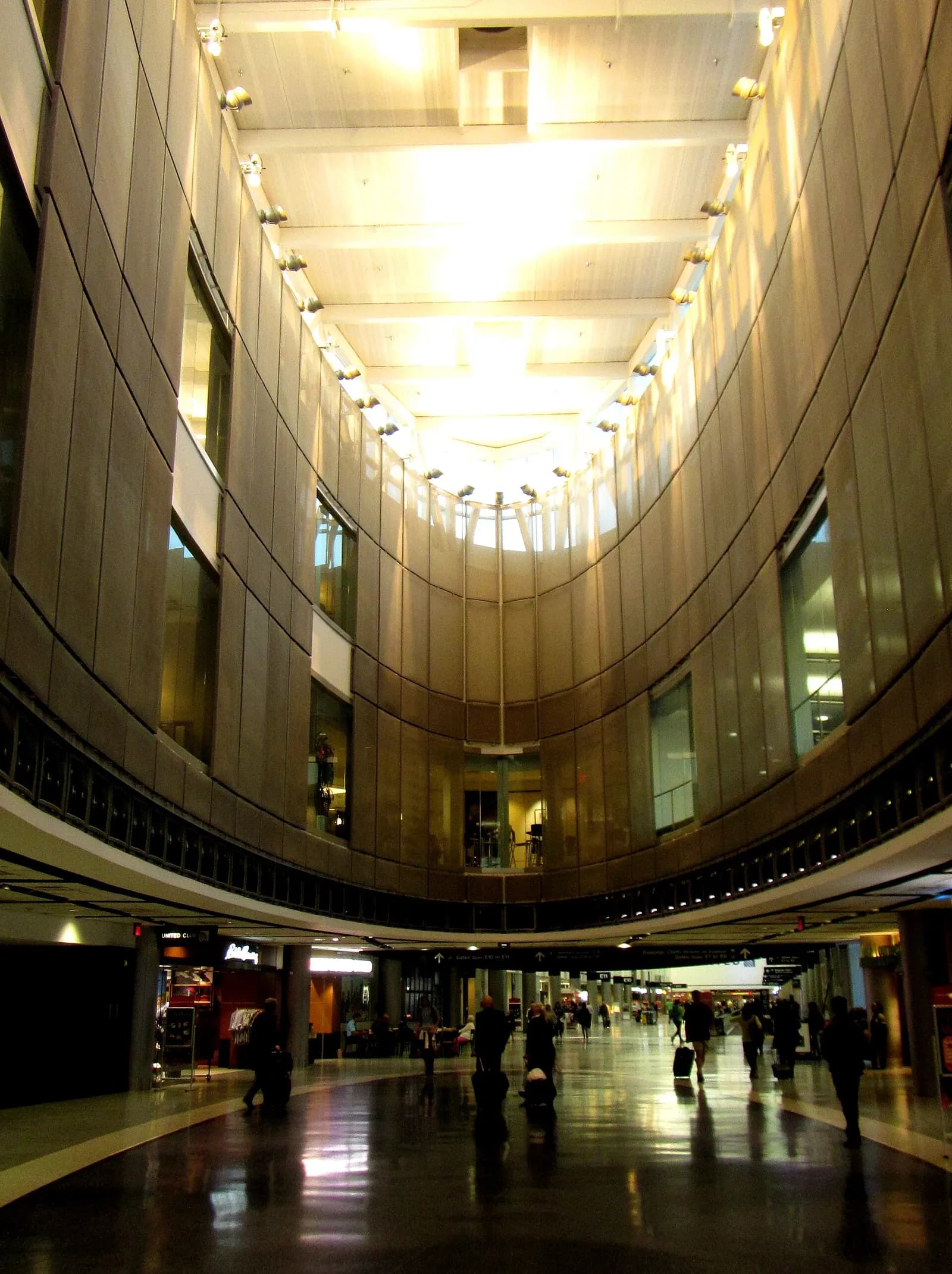 Exterior view of Terminal E at George Bush Intercontinental Airport showing the terminal facade, roadway, and parked vehicles.