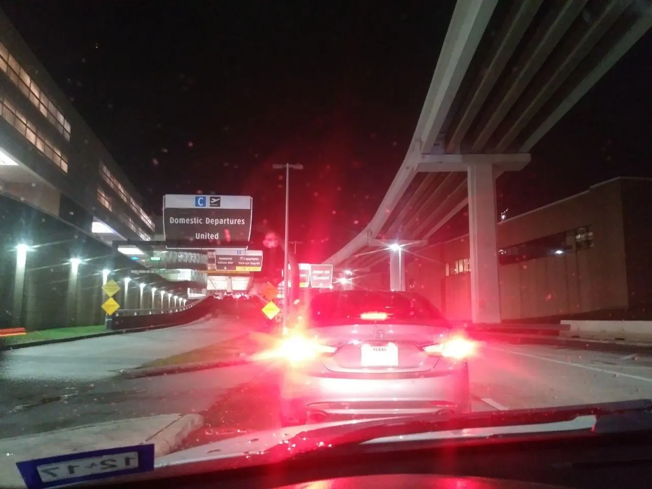 Curbside view of Terminal C with separate upper-level departures roadway and lower-level arrivals lanes marked by signs.
