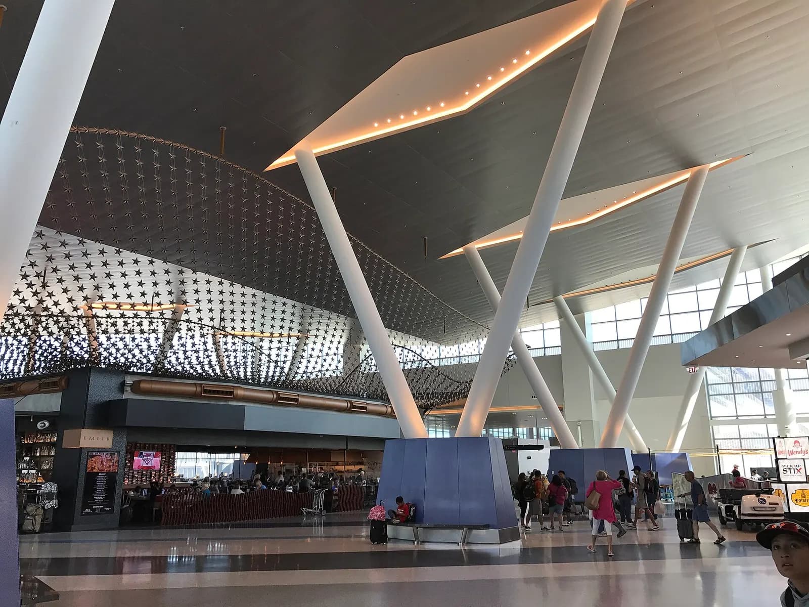 Interior of the north concourse in Terminal C showing gate seating areas, flight information displays, and aircraft visible through tall windows.