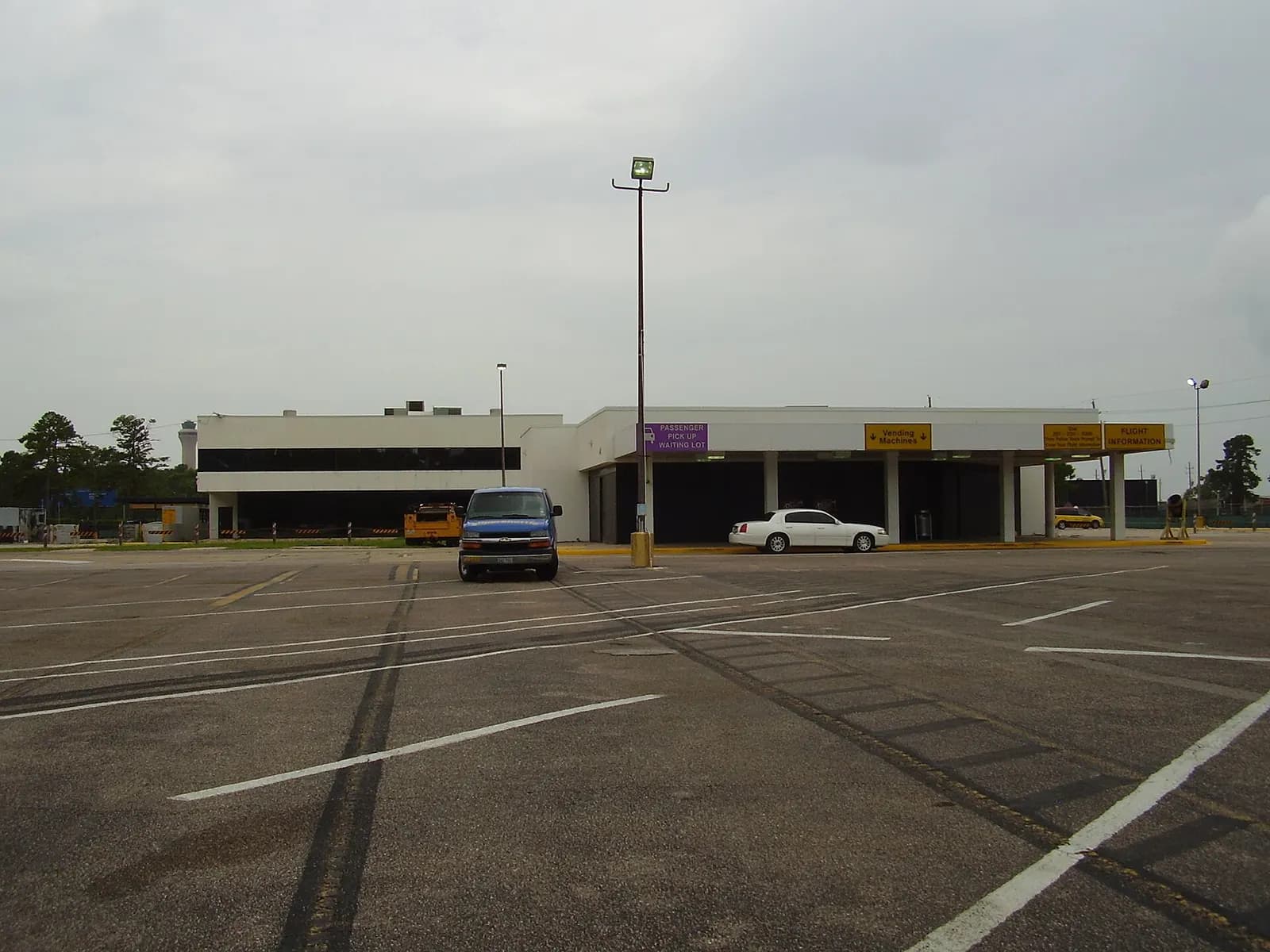 The passenger pickup waiting lot at George Bush Intercontinental Airport with rows of parked cars and signage for cellphone lot holders.