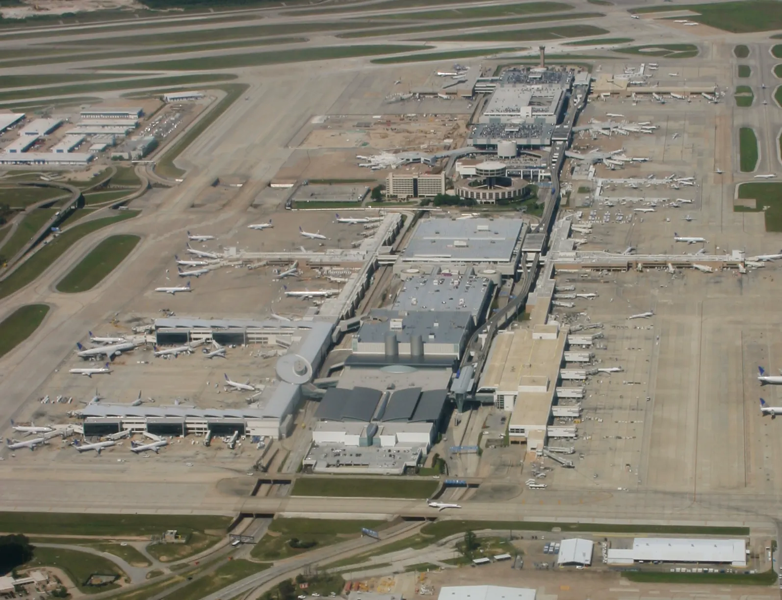 Aerial photograph looking down at George Bush Intercontinental Airport showing parallel runways, clustered terminal buildings, and flat surrounding Texas landscape.