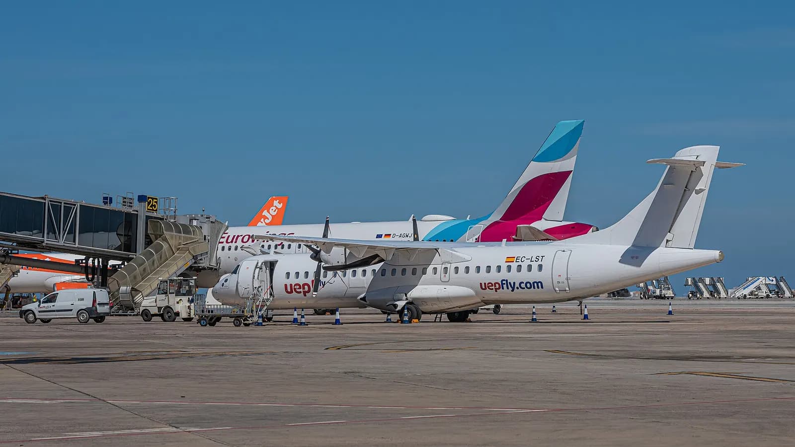 Wide view of Ibiza Airport buildings and airside apron under clear sky.
