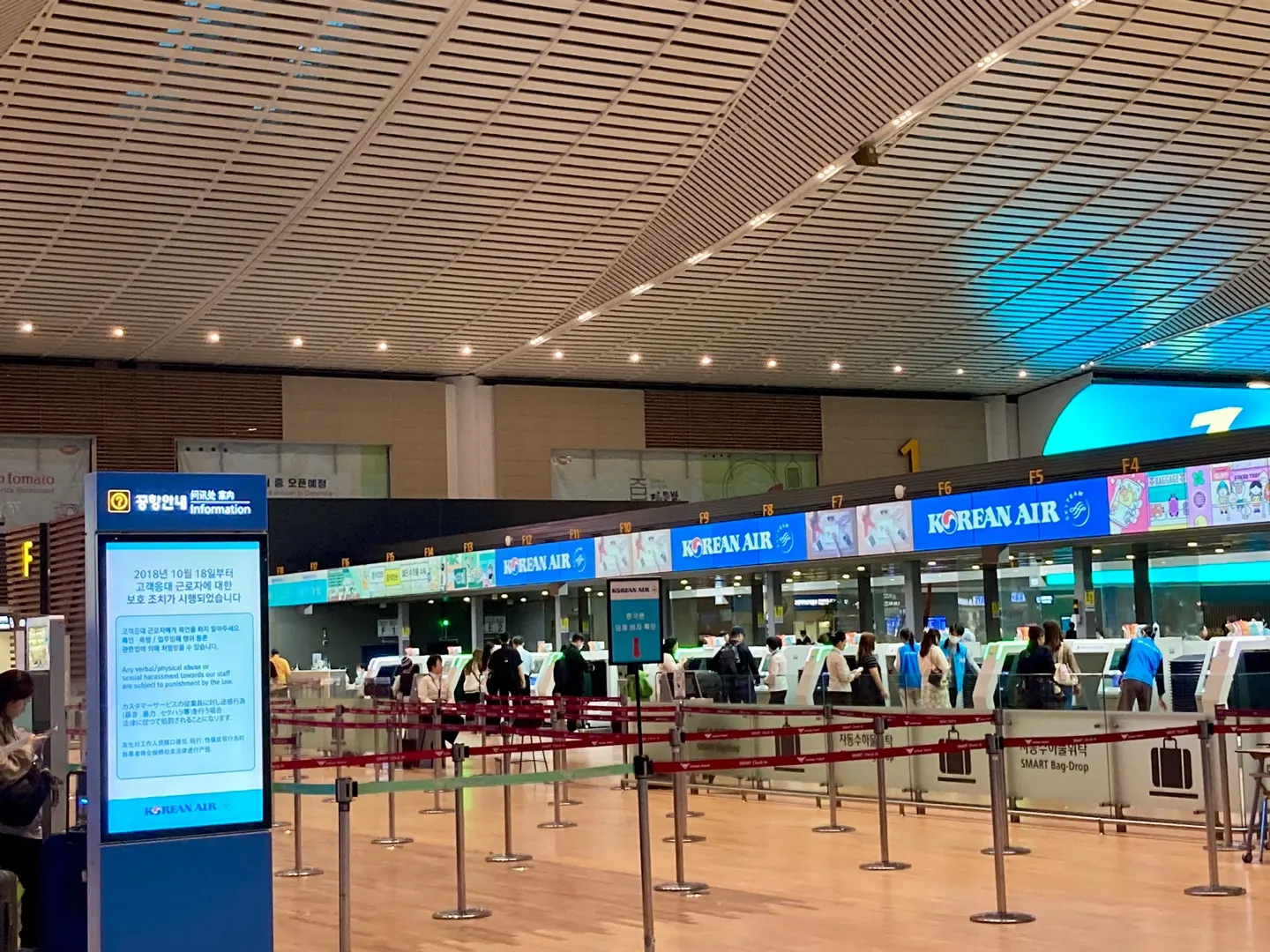 Passengers queue at Korean Air check-in counters in Terminal 2, with overhead signs marking the F check-in zone.