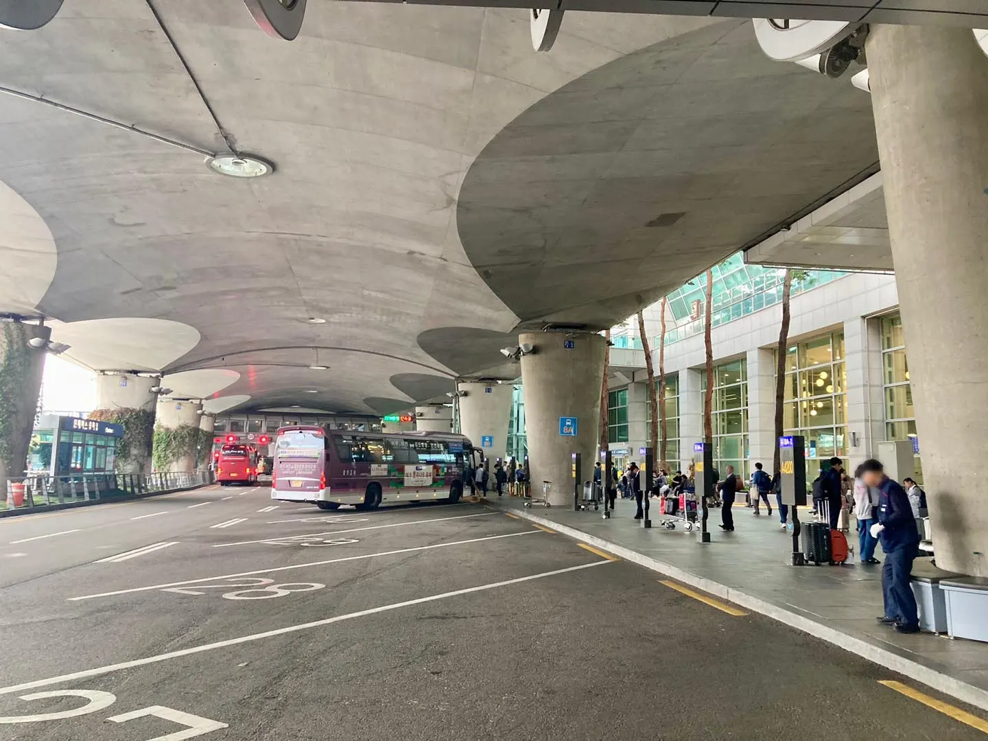 Outdoor bus boarding bays at Incheon Airport Terminal 1 with numbered stops and signs for city and regional bus routes.