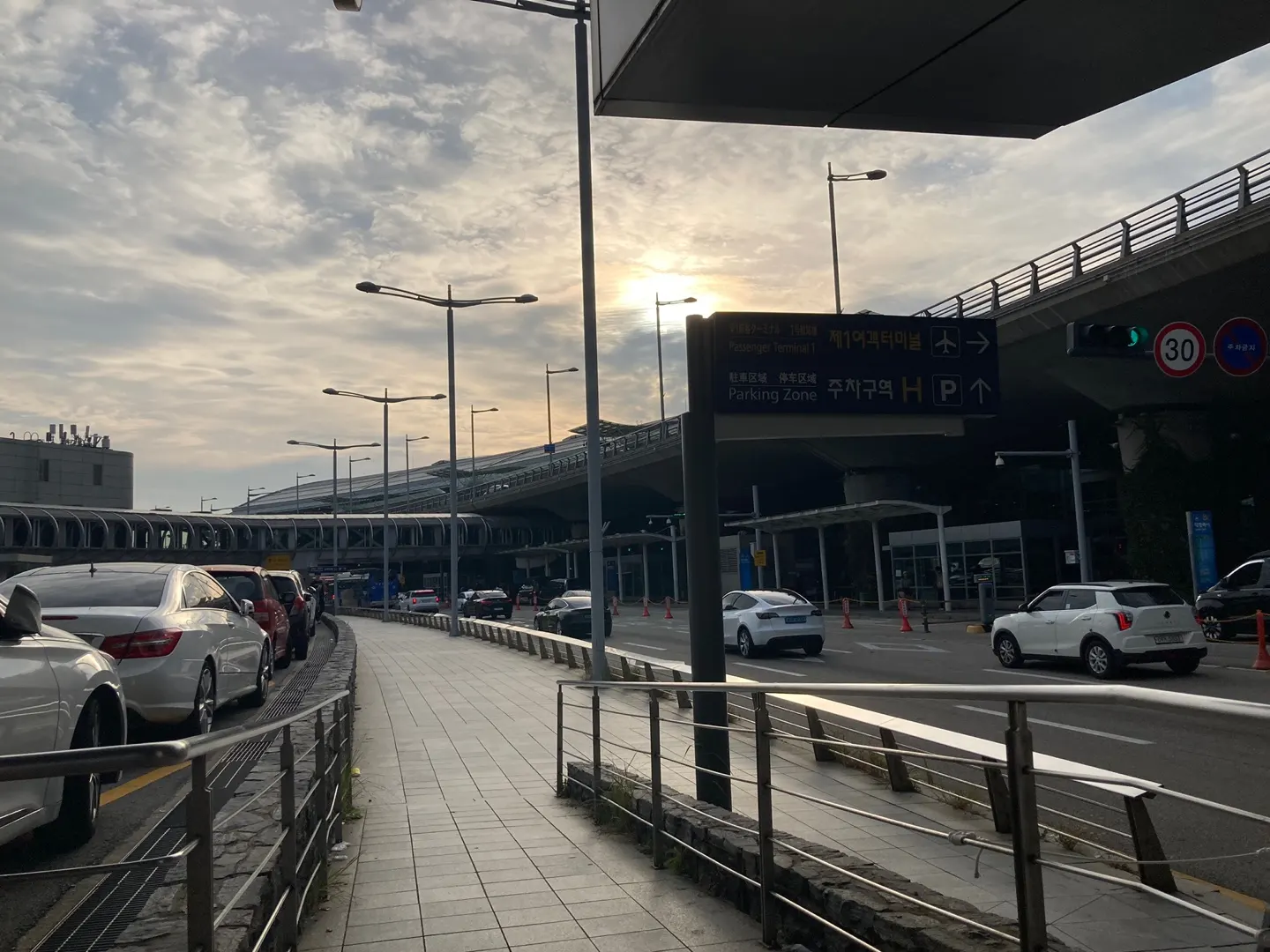 Exterior view of Incheon Airport Terminal 1 showing the multi-story glass-fronted building, covered walkways, and the curbside drop-off area.