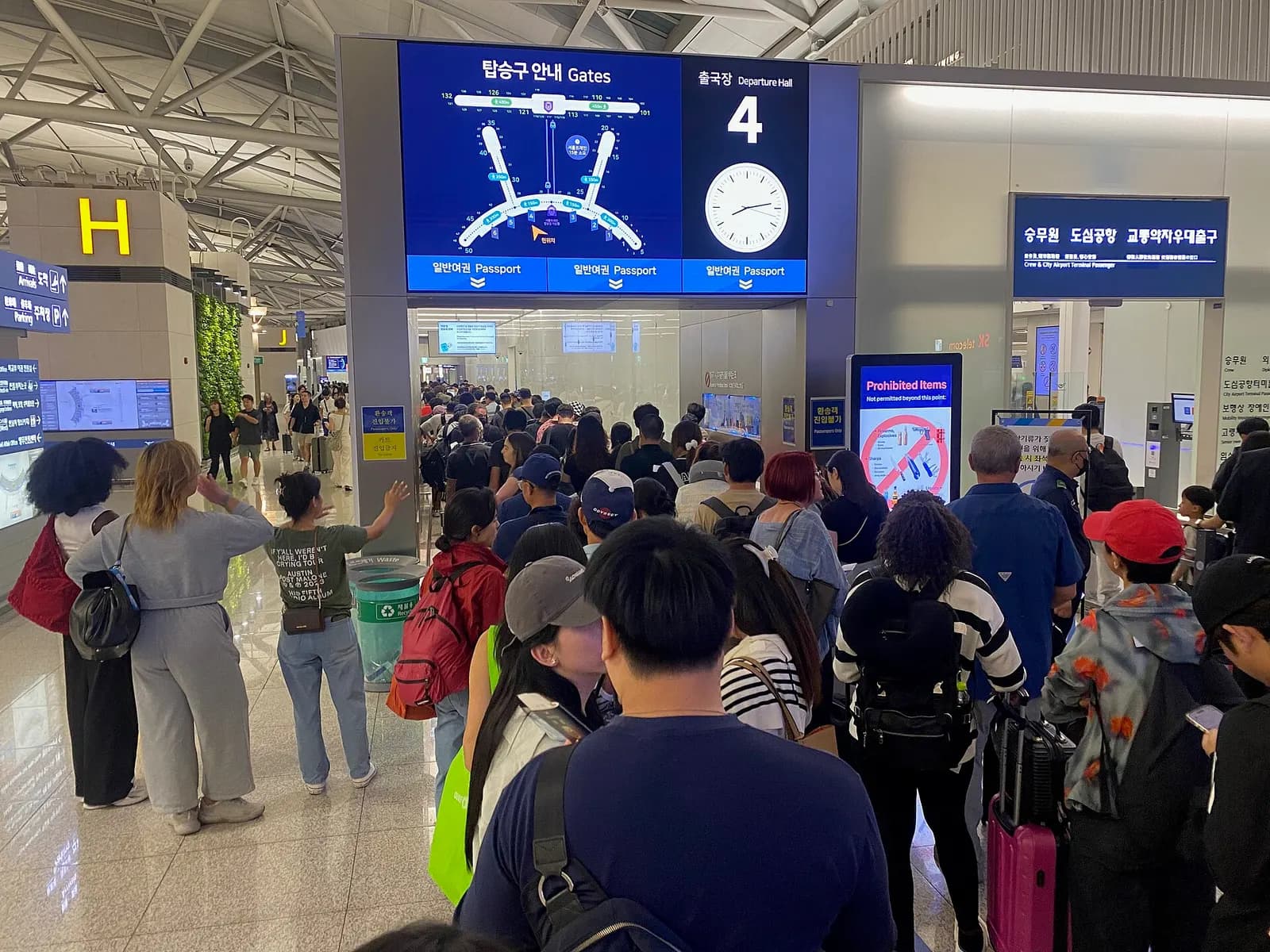 A corridor leading to departure gates at Incheon Airport with gate numbers, flight information displays, and passengers heading toward boarding areas.