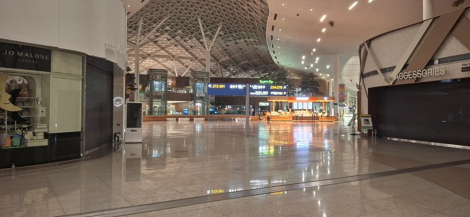 Wide exterior panorama of Incheon Airport Terminal 2 with its long modern facade, parking areas, and roadways in front.