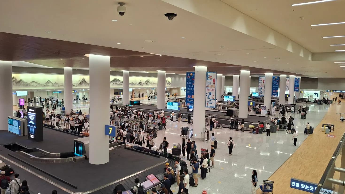 Terminal 2 arrivals hall at Incheon Airport with baggage claim carousels, open hall space, and directional signage for exiting passengers.