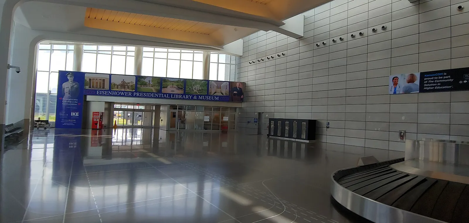Baggage-claim hall at Wichita Eisenhower National Airport with carousels and arriving passengers.