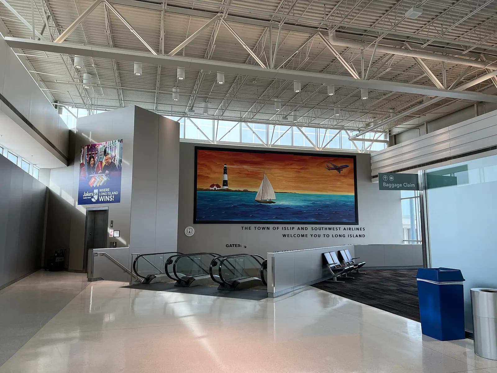 Concourse A at Long Island MacArthur Airport on 20 February 2023, approaching the escalators to Concourse B under a Fire Island mural.