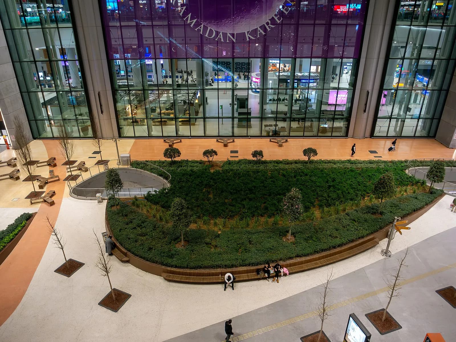 Landscaped green garden with trees and paved paths at the entrance area of Istanbul Airport.