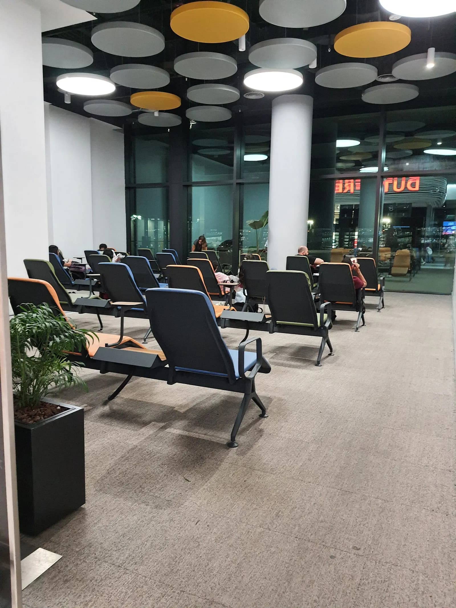 Airport lounge seating area at Istanbul Airport with chairs and tables where waiting passengers can rest.