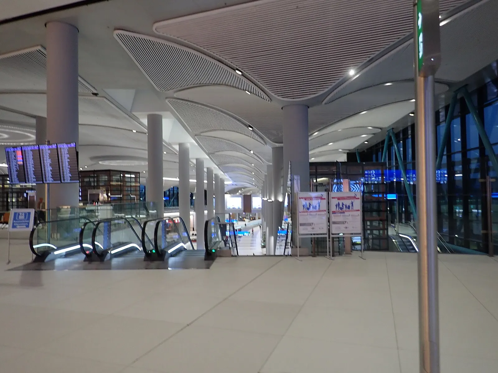 Long airside concourse corridor at Istanbul Airport at the start of the D gates section, with signage and moving walkways.