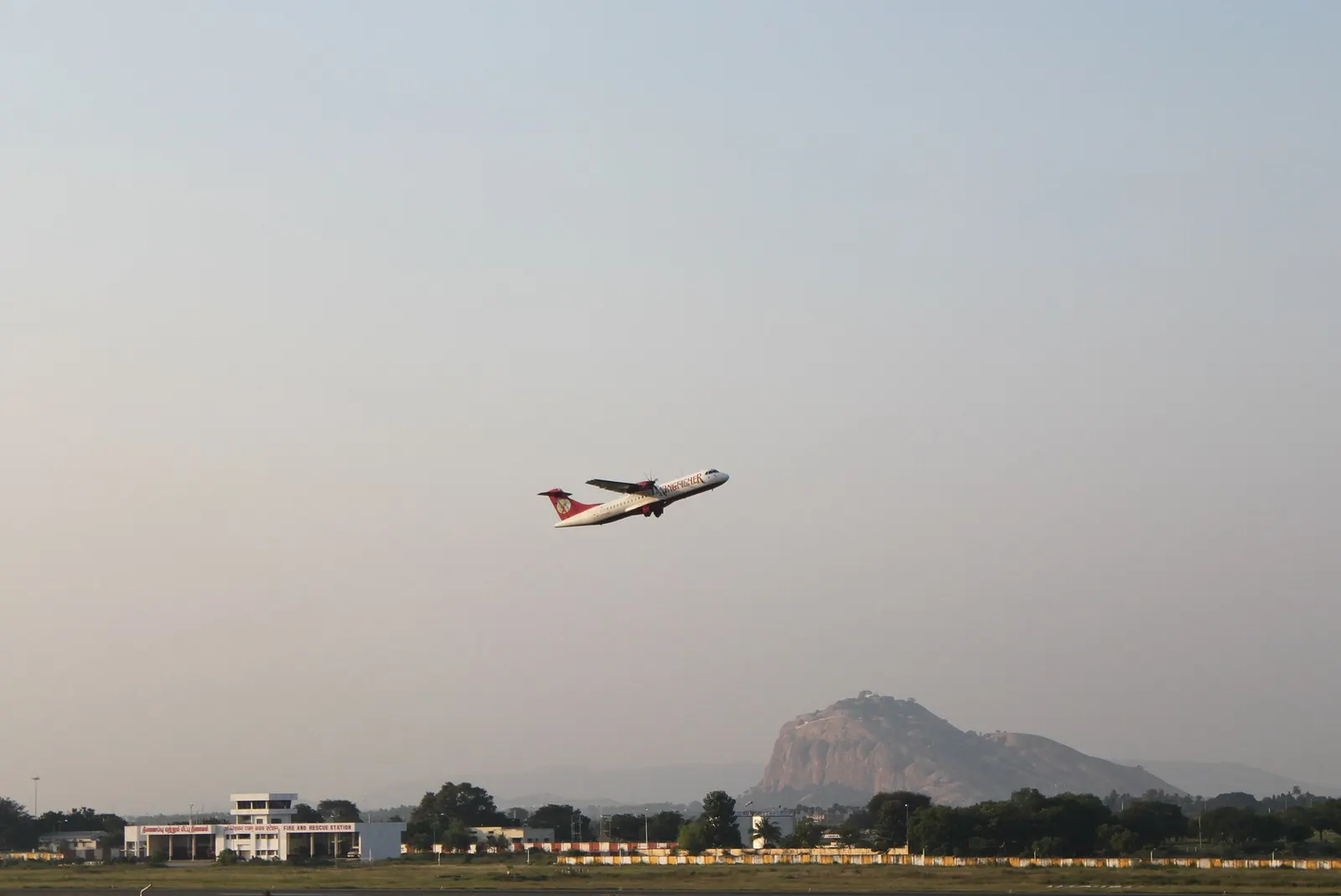 This picture shows an ATR mini jet of Kingfisher Airlines taking off from The Madurai Airport (before inauguration of the new terminal), with the Tiruparankundram Hill in the Backdrop.