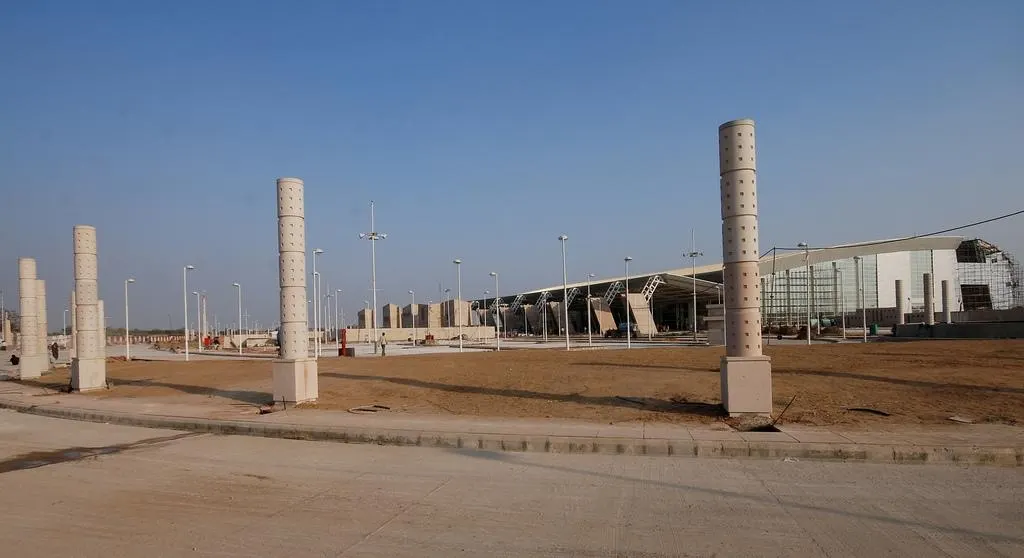 Daytime exterior of Jaipur Airport terminal building with curved roof and approach road.