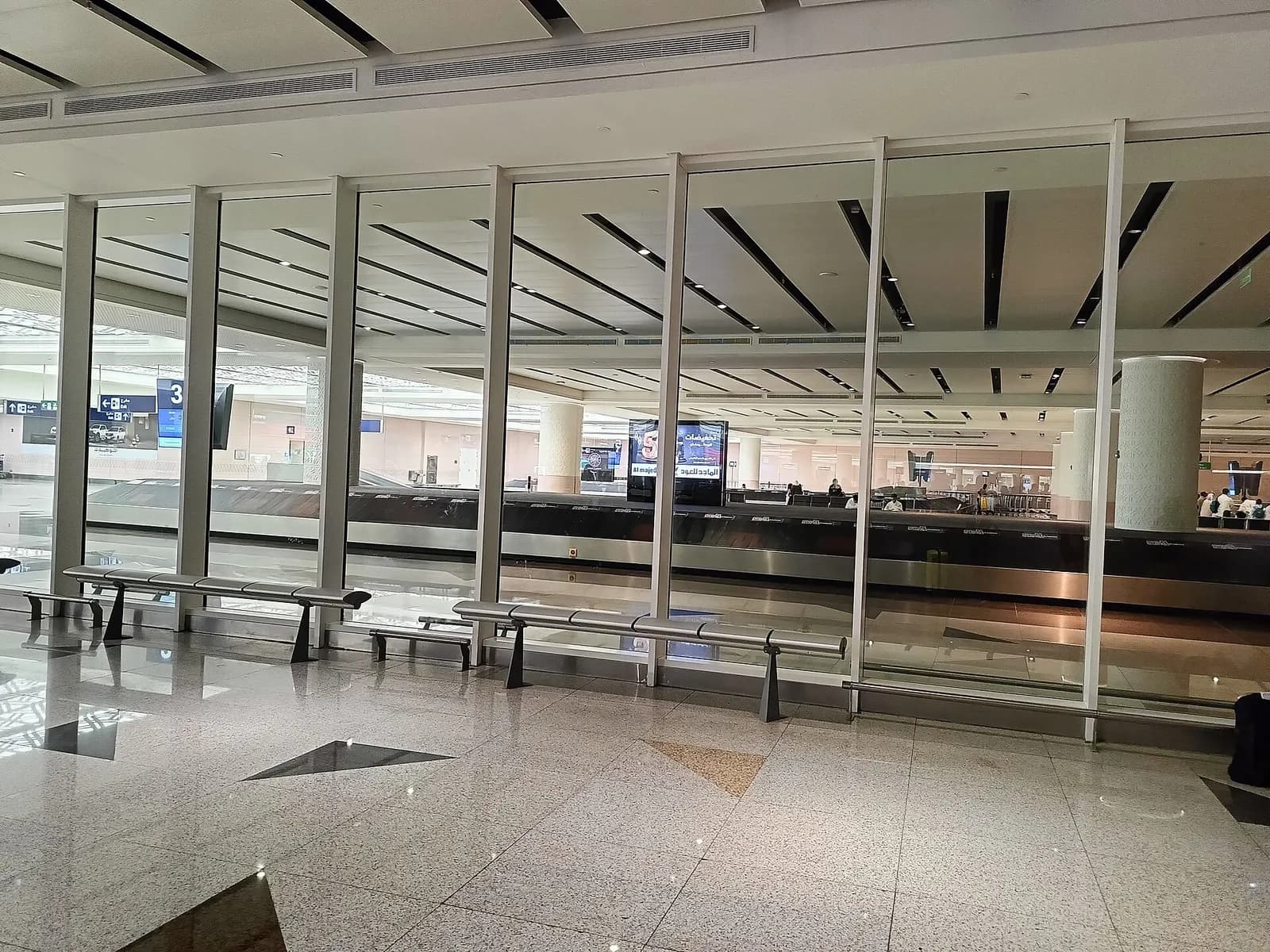 Travelers fill a bright terminal concourse with check-in counters, signage, and departure screens visible throughout the hall.