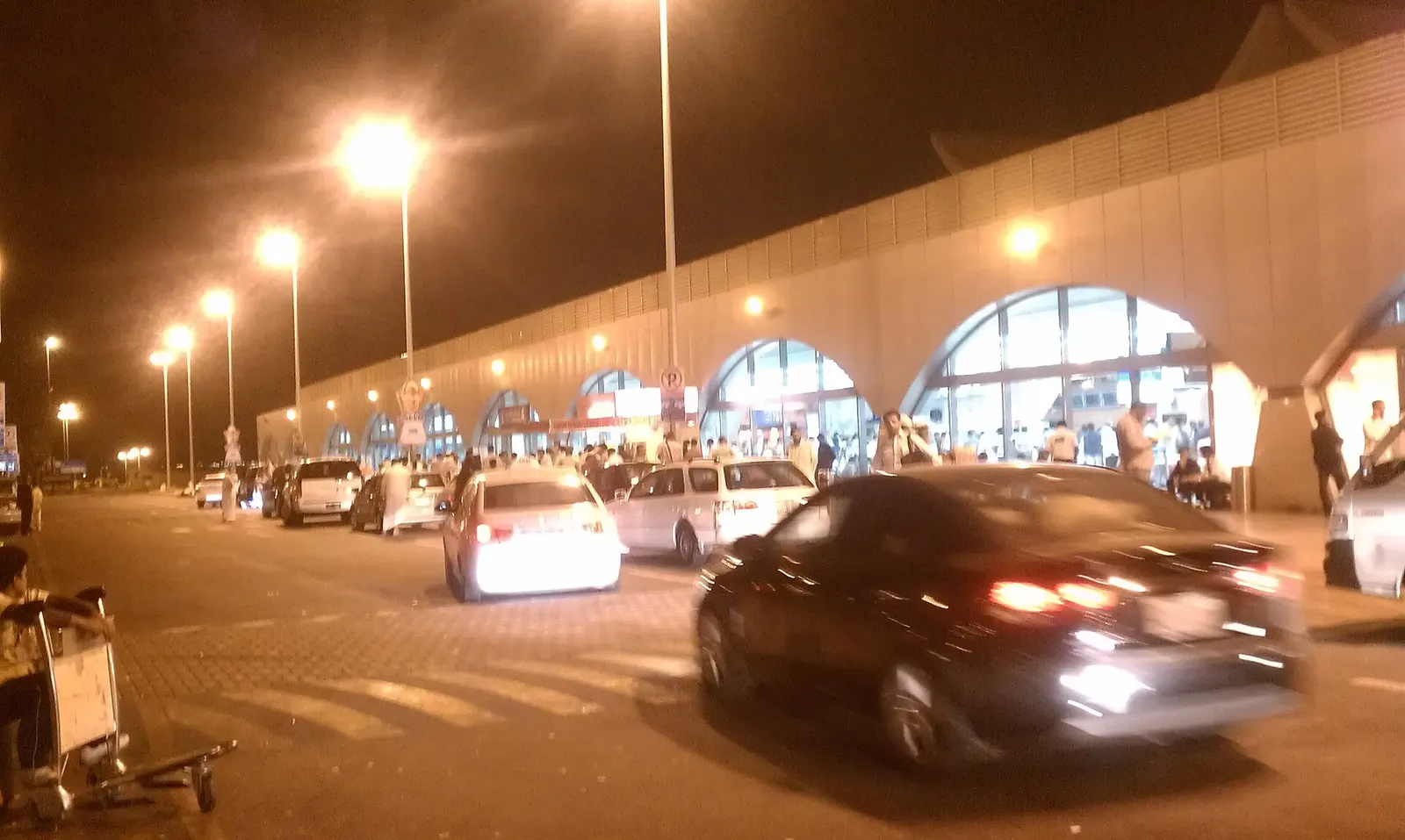 Jeddah airport terminal buildings and runway lights glow against a deep blue night sky.