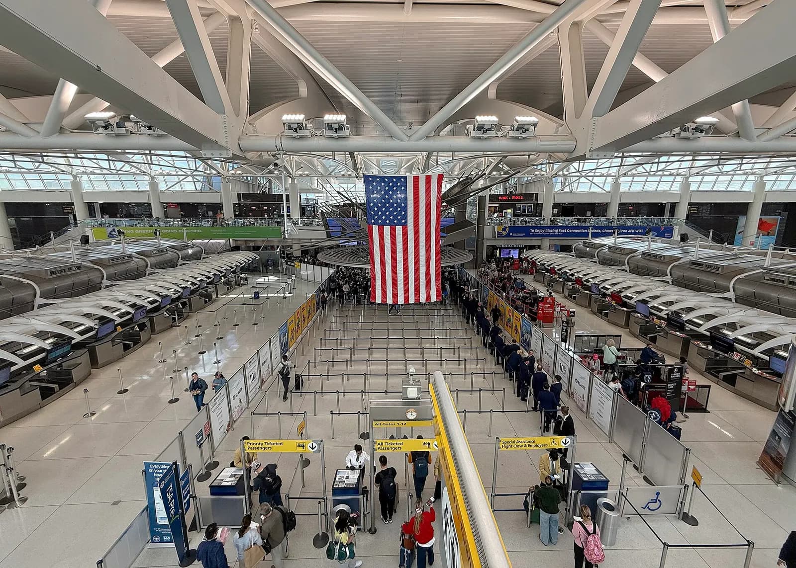 The check-in hall inside Terminal 1 has airline counters, departure screens, and travelers with luggage moving through the bright, open concourse.
