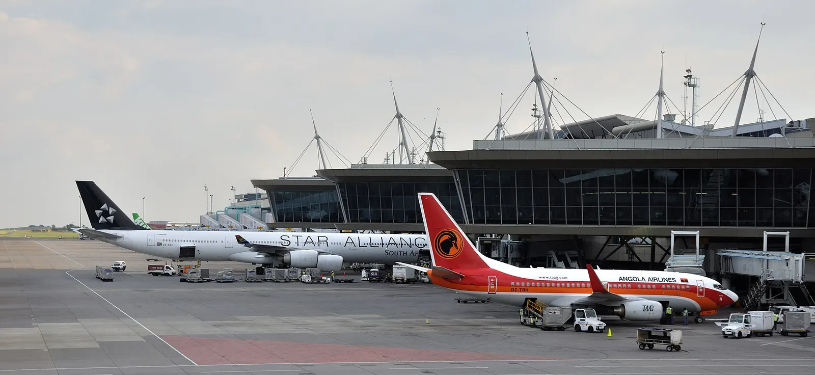 A panoramic view across the runways, taxiways, and terminal buildings at O.R. Tambo International Airport from an outside vantage point.