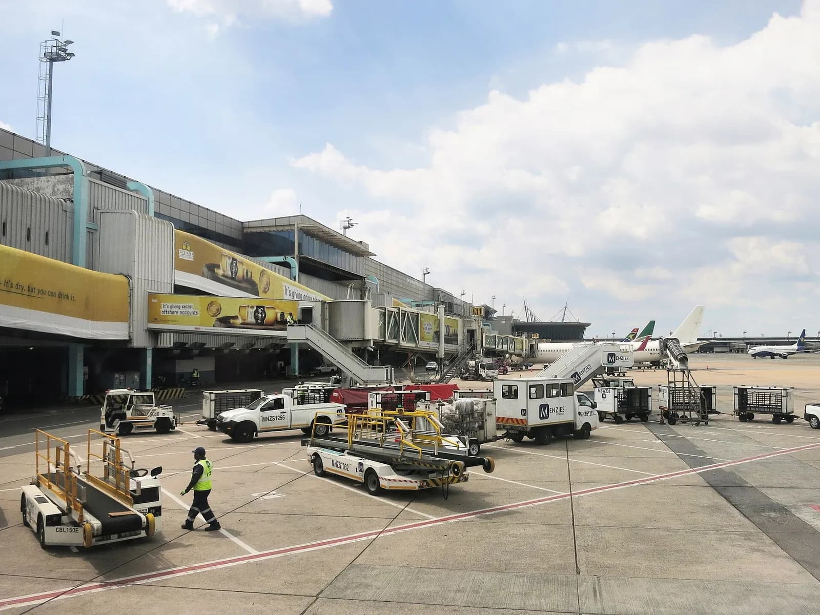 Ground-handling equipment and workers on the ramp outside the domestic terminal at O.R. Tambo International Airport.