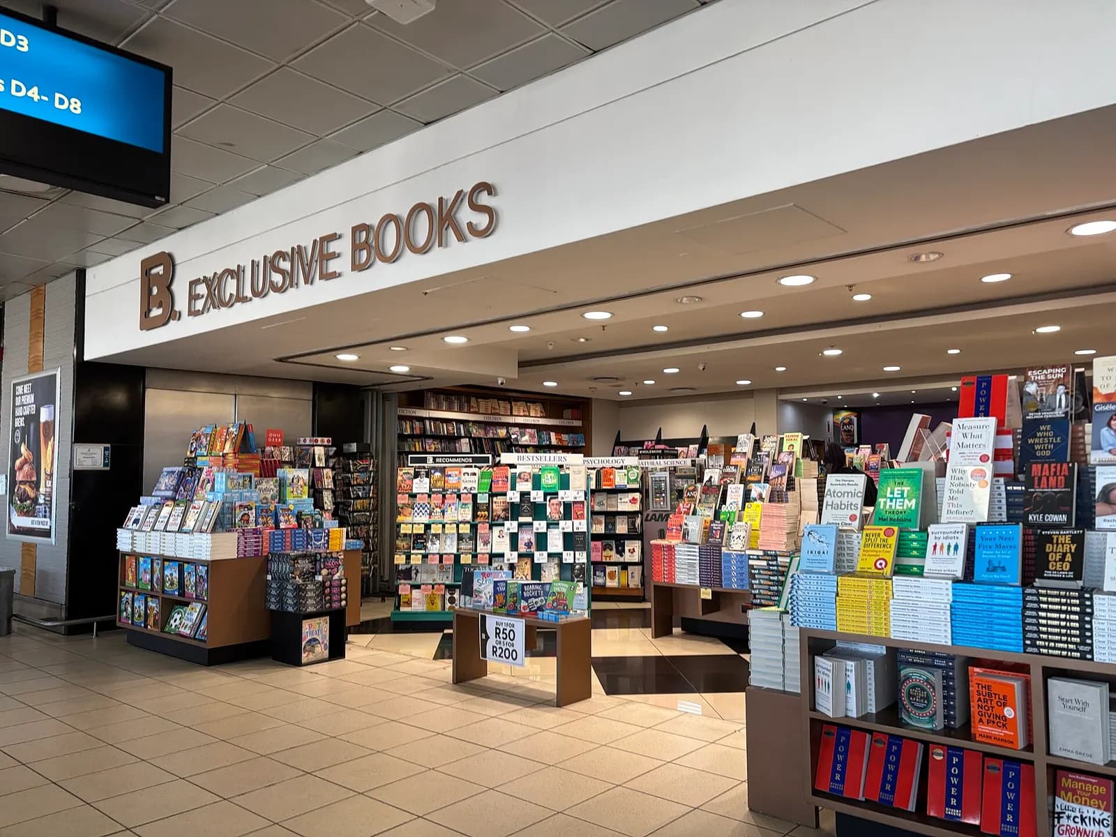 The Exclusive Books bookstore inside Terminal B at O.R. Tambo International Airport, with shelves of books and a bright retail interior.