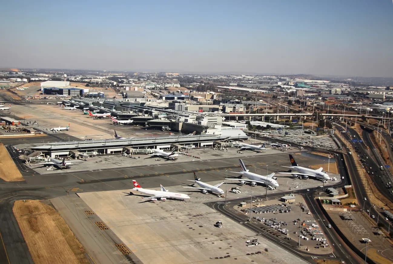 An aerial view of O.R. Tambo International Airport surrounded by highways, rail lines, and commercial development forming the Ekurhuleni aerotropolis.