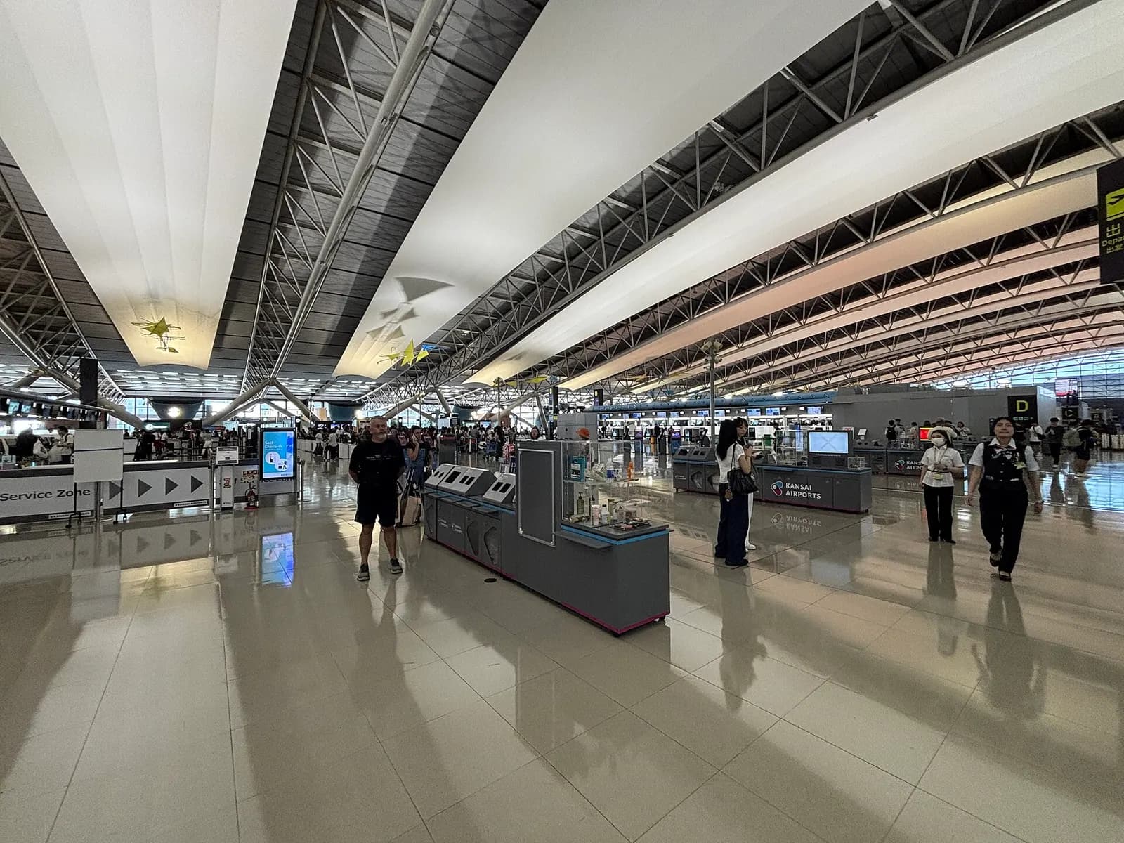 Bright, spacious departure level inside Terminal 1 with check-in counters, overhead signage, and travelers.