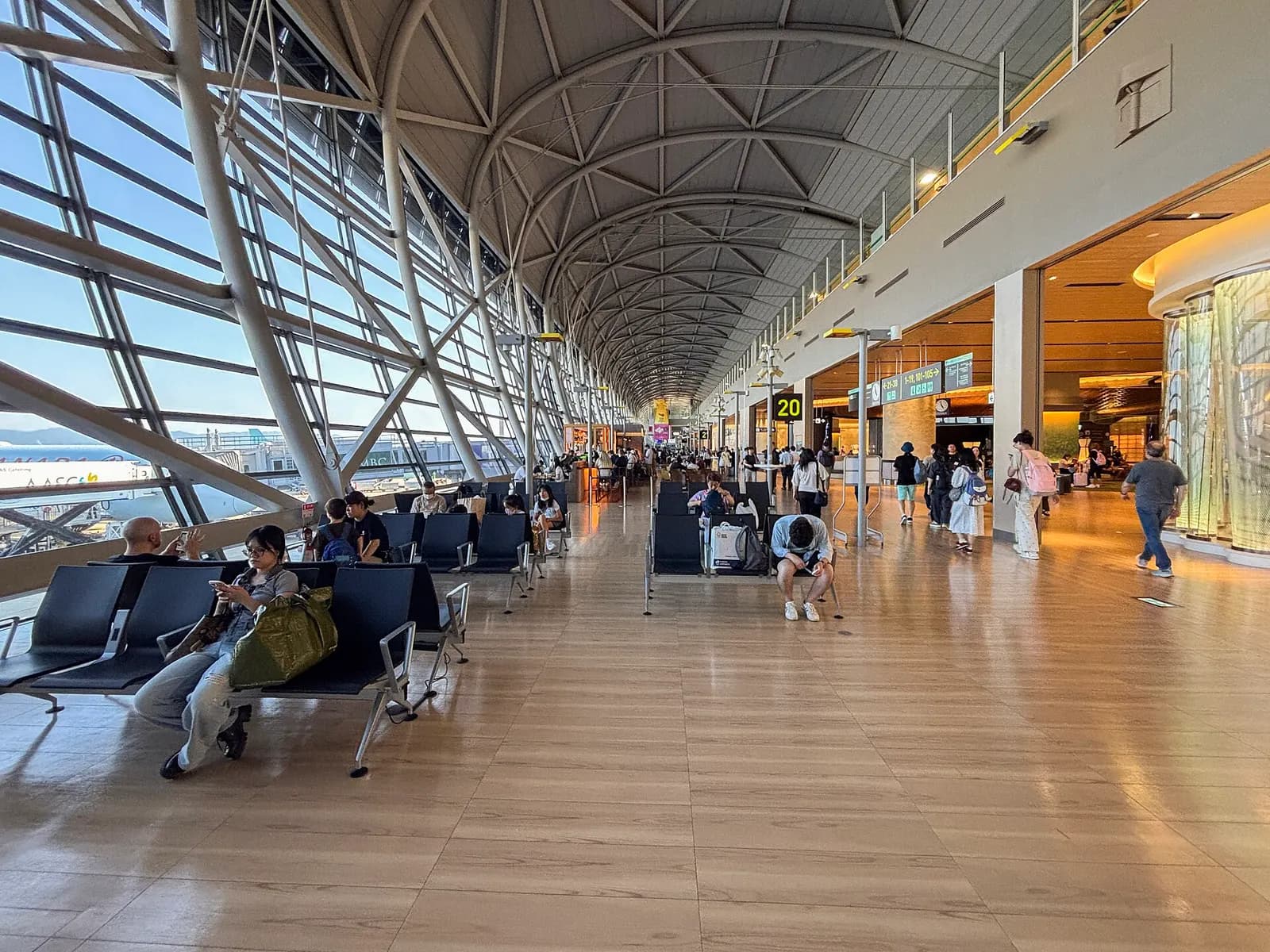 Gate seating area at Terminal 1 Gate 20 with an aircraft parked at the jet bridge visible through the windows.