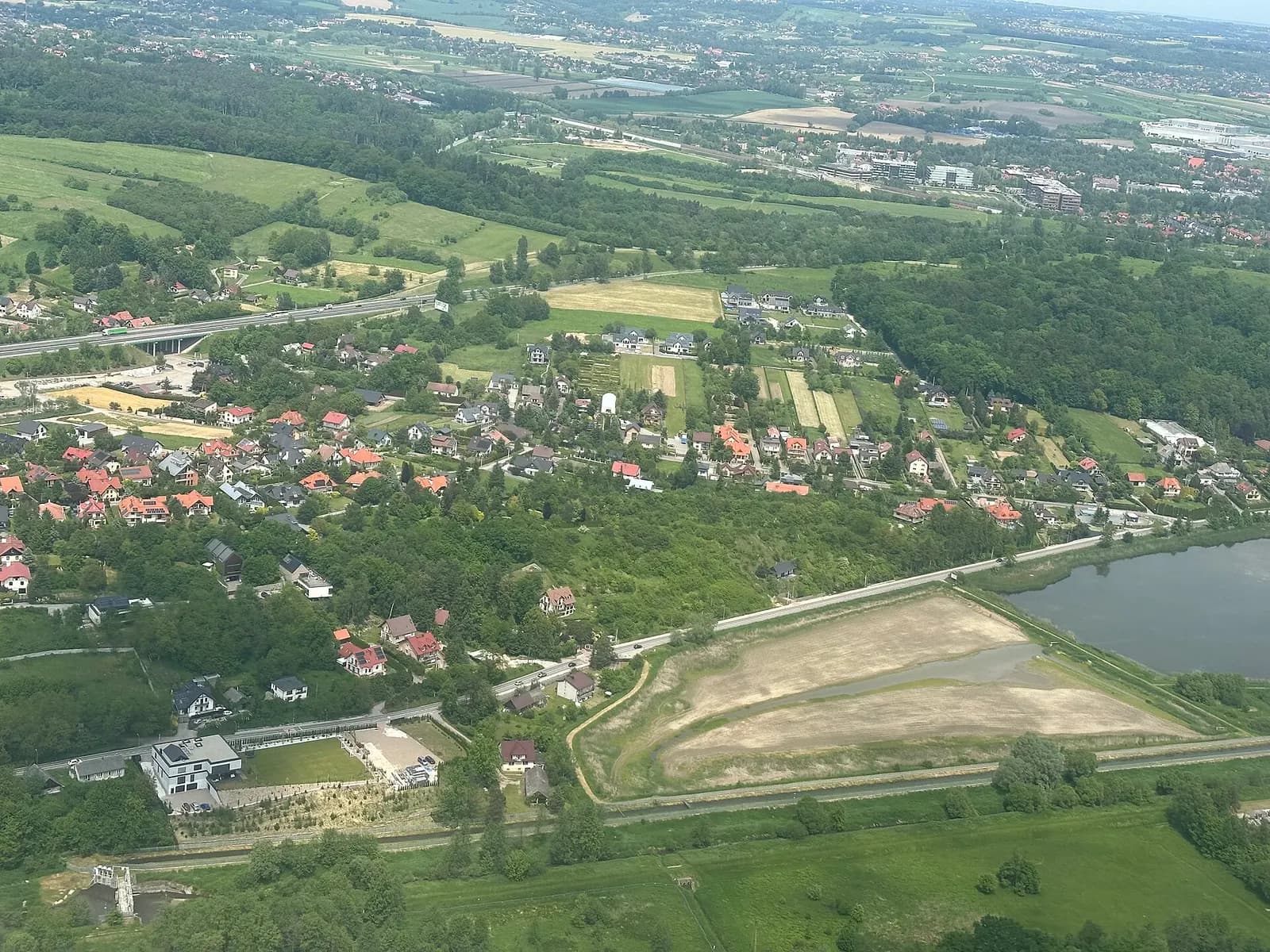 Aerial view of Kraków John Paul II International Airport taken from an aircraft shortly after takeoff, showing runways and terminal buildings below.