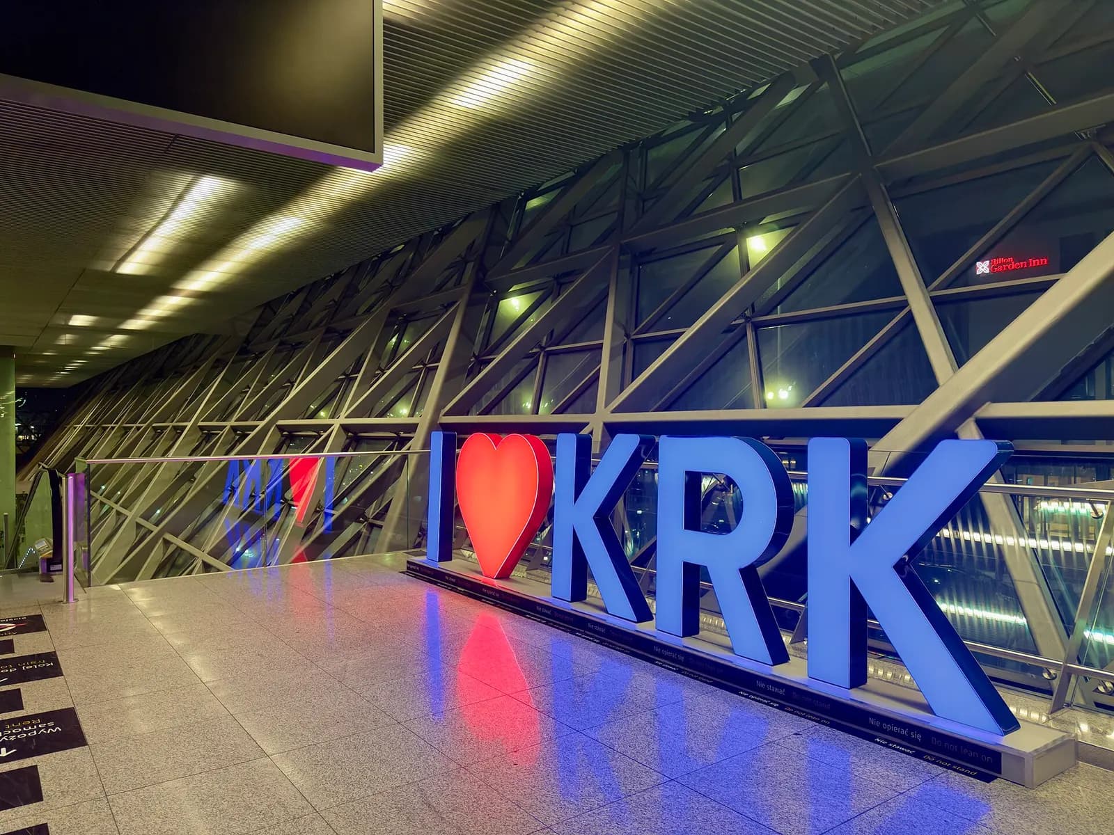 A large ILoveKRK welcome sign displayed inside Kraków Airport's passenger terminal.
