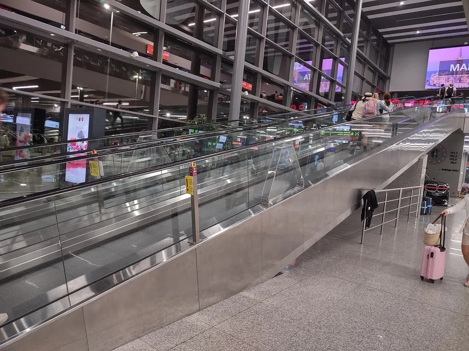 A covered passenger boarding ramp at Terminal B with a motorized downward ramp and stairs for aircraft access.