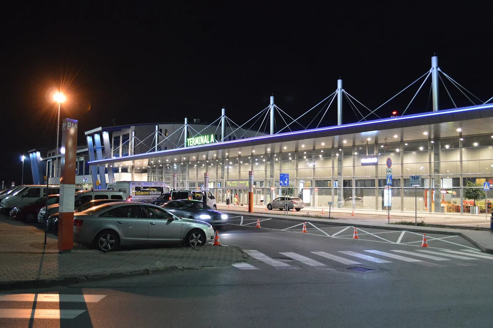 Katowice Airport terminal buildings and airfield lighting glowing against a dark night sky.